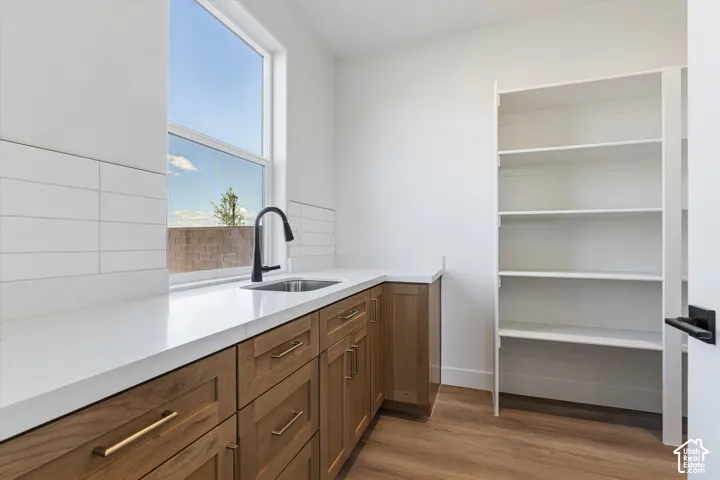 Window-mounted sink with a matte black faucet, white countertop, wood-finish cabinetry, and built-in shelving