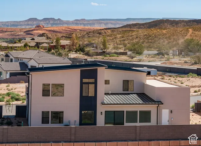 Contemporary architecture featuring a light-colored stucco exterior, dark accent panels, and a metal roof
