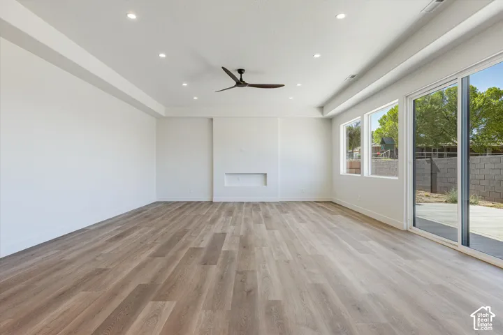 Spacious living area featuring wood-finish flooring, recessed lighting, a modern ceiling fan, and a built-in fireplace niche
