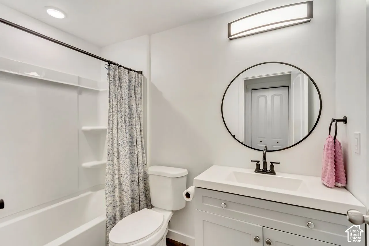 White vanity with an integrated sink and black faucet, complemented by a round framed mirror