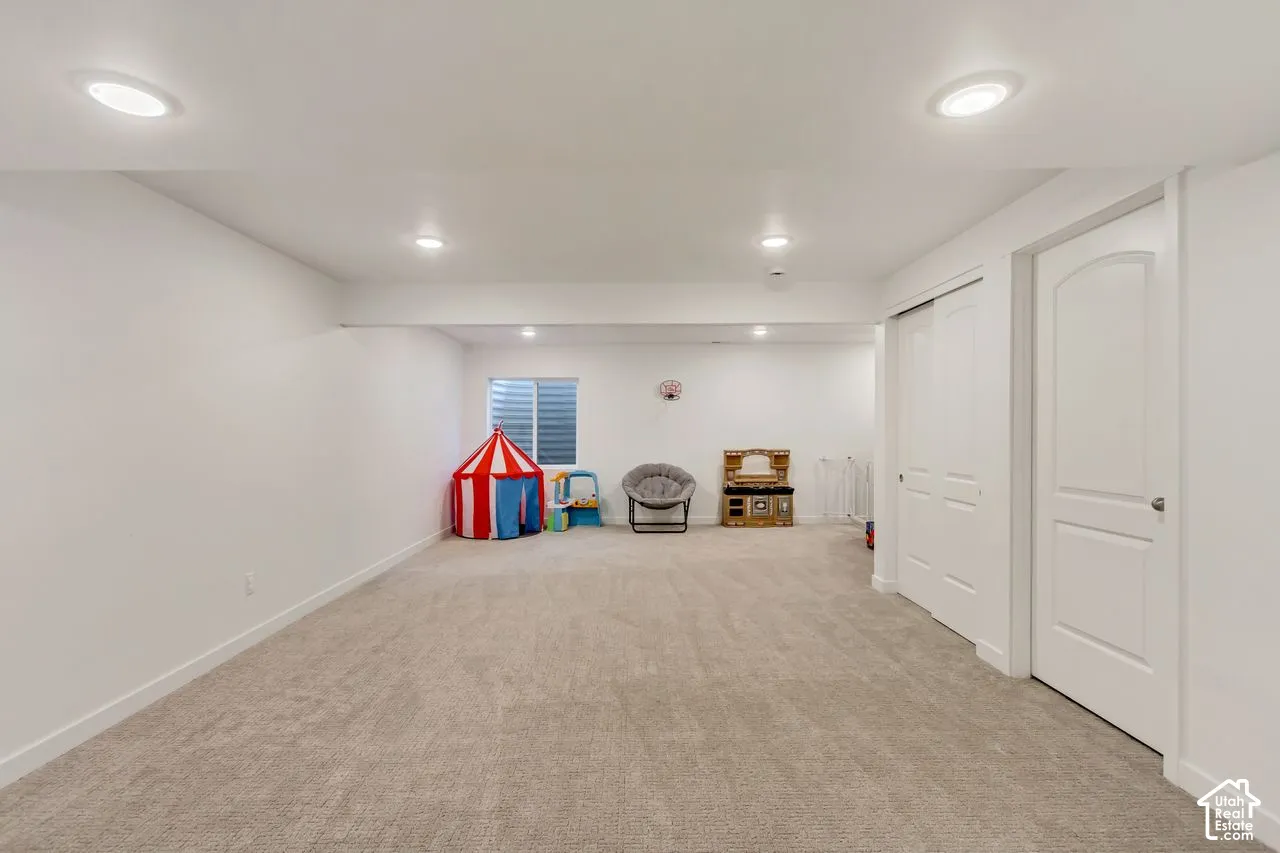 Spacious room with light-colored carpeting, recessed lighting, and white walls