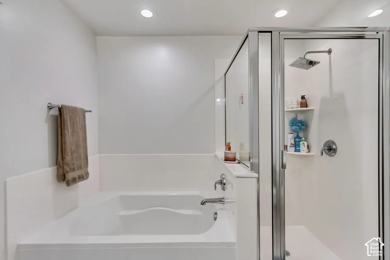 Recessed lighting, built-in bathtub, chrome towel bar, glass-enclosed shower, rain shower head