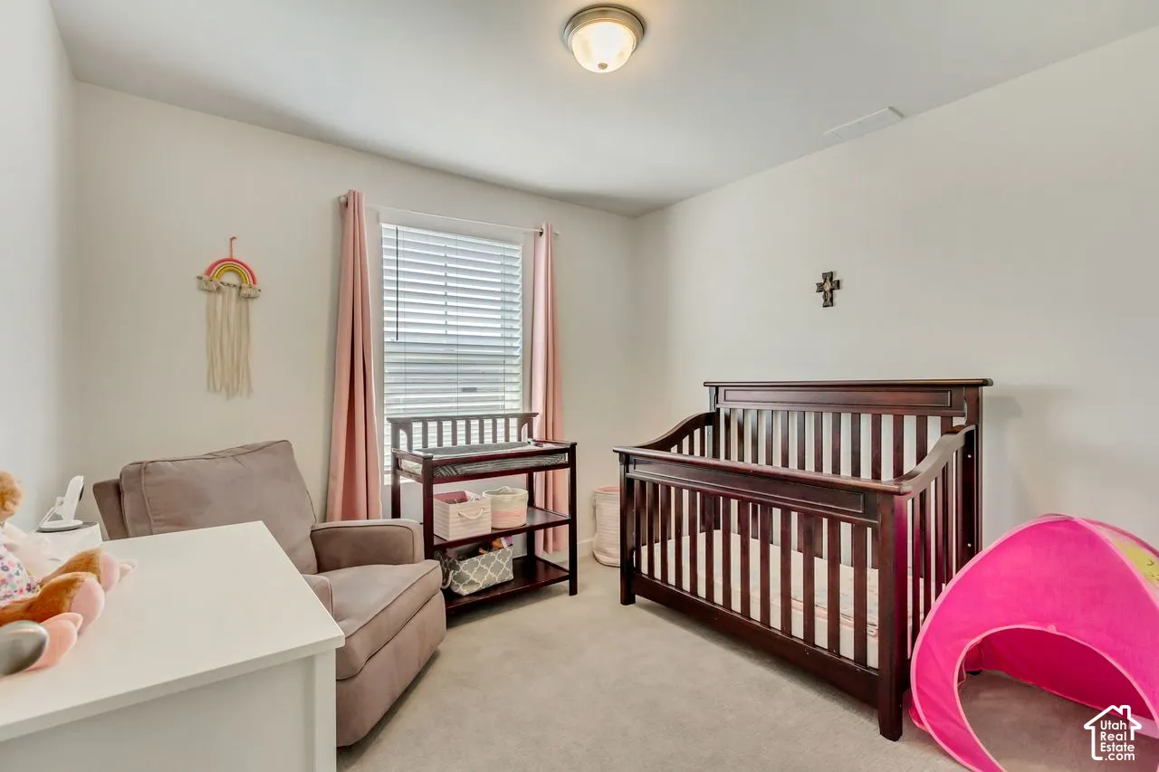 Recessed ceiling light, neutral wall color, window with blinds, carpeted flooring, and a dark wood-finish crib