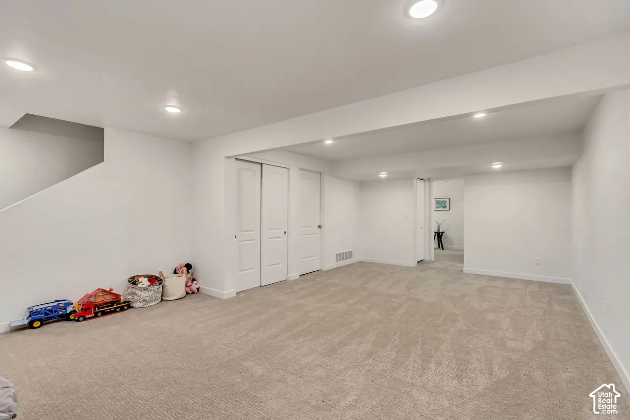 Spacious room with recessed lighting, light-toned carpet, white walls, and built-in closet with bifold doors