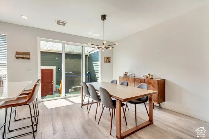 Recessed lighting, wood-finish flooring, modern ceiling fixture, sliding glass door, white walls