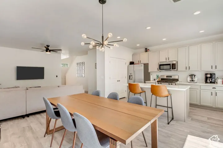 Open-concept living space featuring a modern kitchen, white cabinetry, stainless steel appliances, and an island with counter seating
