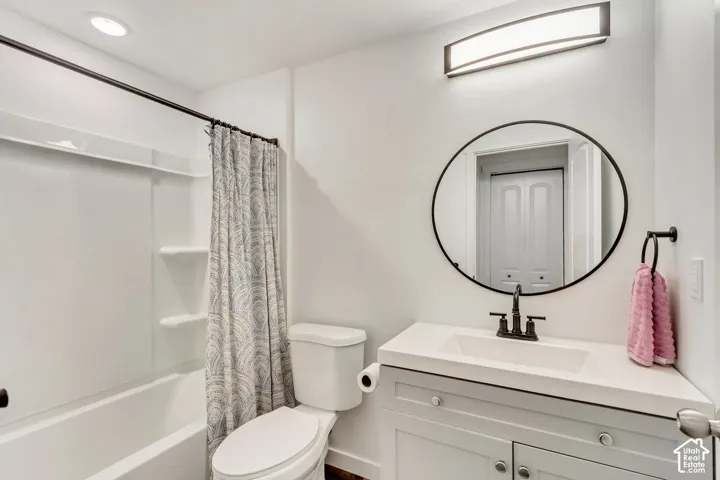 White vanity with an integrated sink and black faucet, complemented by a round framed mirror