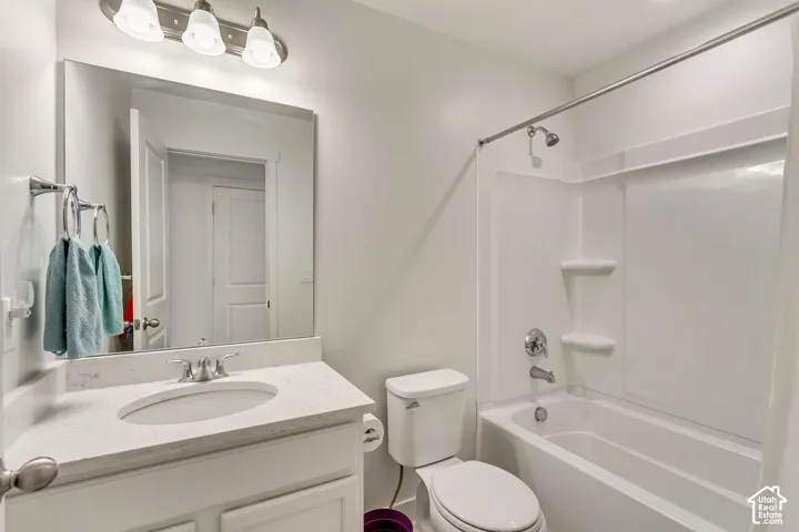 Vanity with an integrated sink and light-toned countertop, modern chrome faucet, large frameless mirror, and a full bathtub with a shower kit