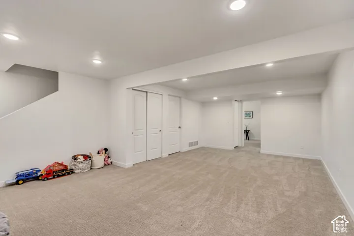 Spacious room with recessed lighting, light-toned carpet, white walls, and built-in closet with bifold doors