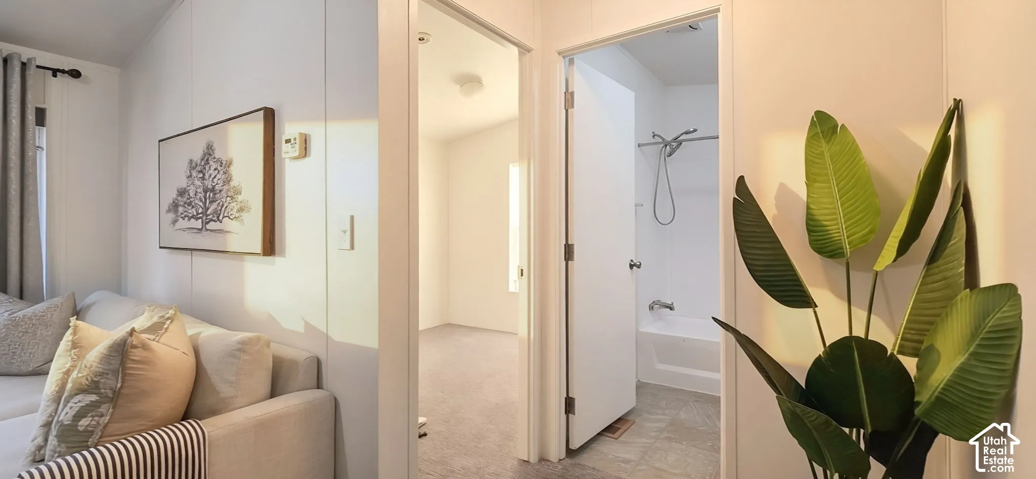 White interior wall paneling, light gray carpet flooring, white interior doors, and a white bathtub with a shower fixture