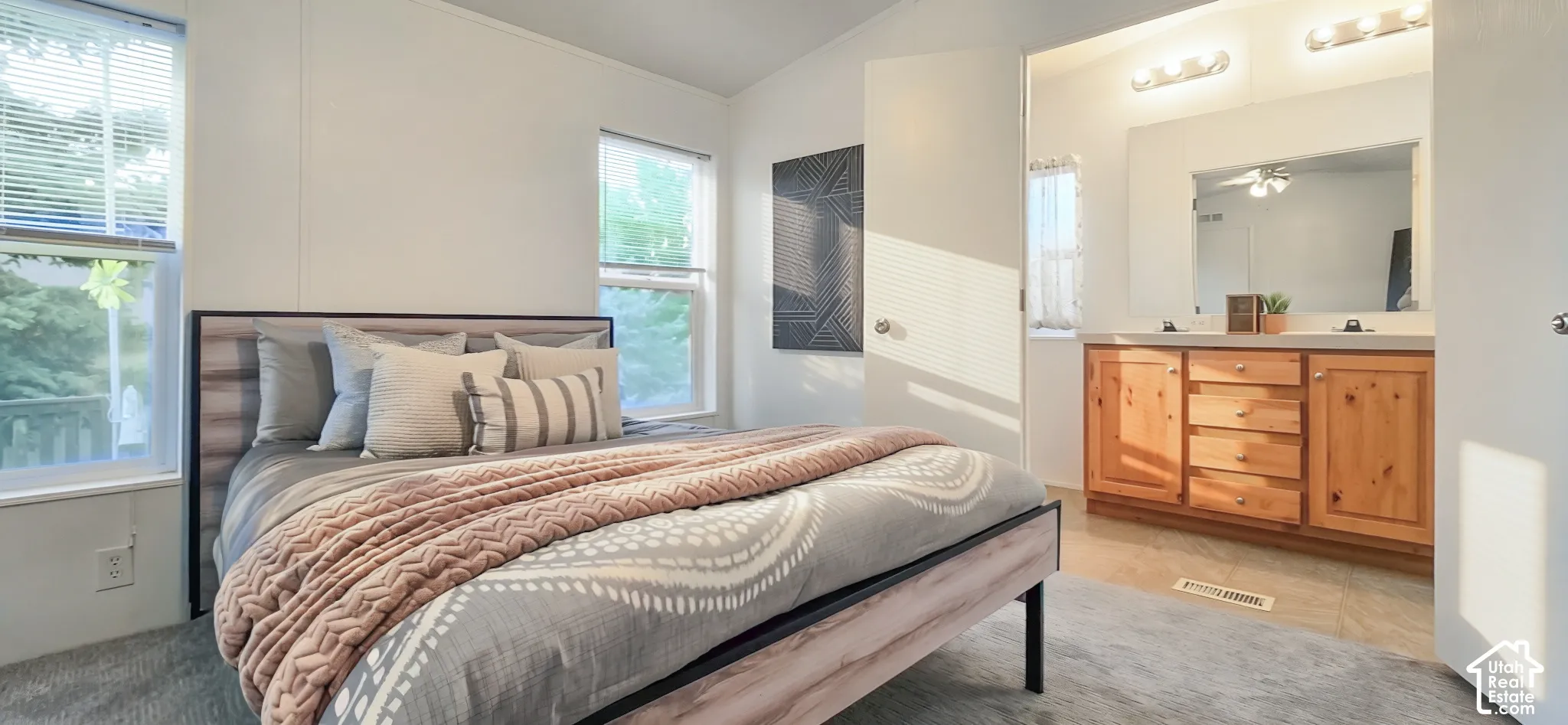 Carpeted bedroom with multiple windows and a door opening to a vanity area