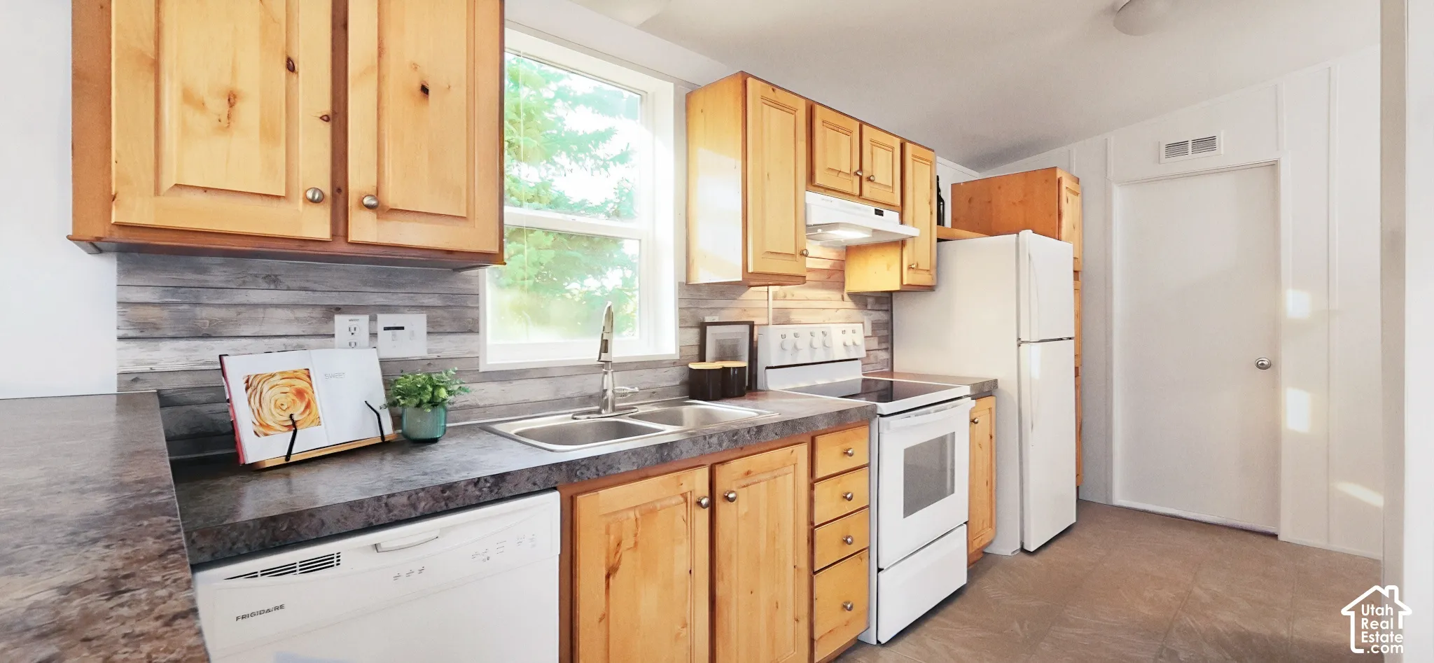 Wood-finish cabinetry, dual basin stainless steel sink, wood-finish backsplash, and laminate countertops