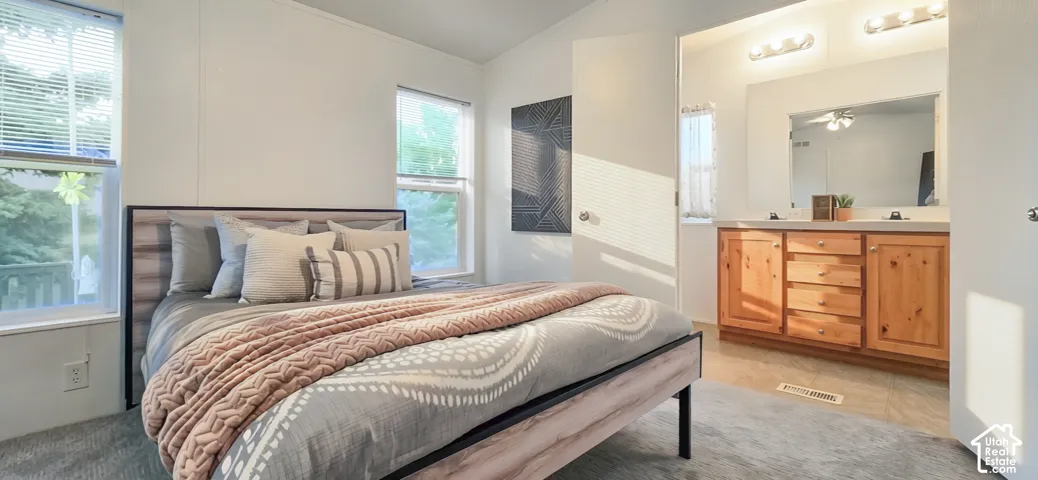 Carpeted bedroom with multiple windows and a door opening to a vanity area