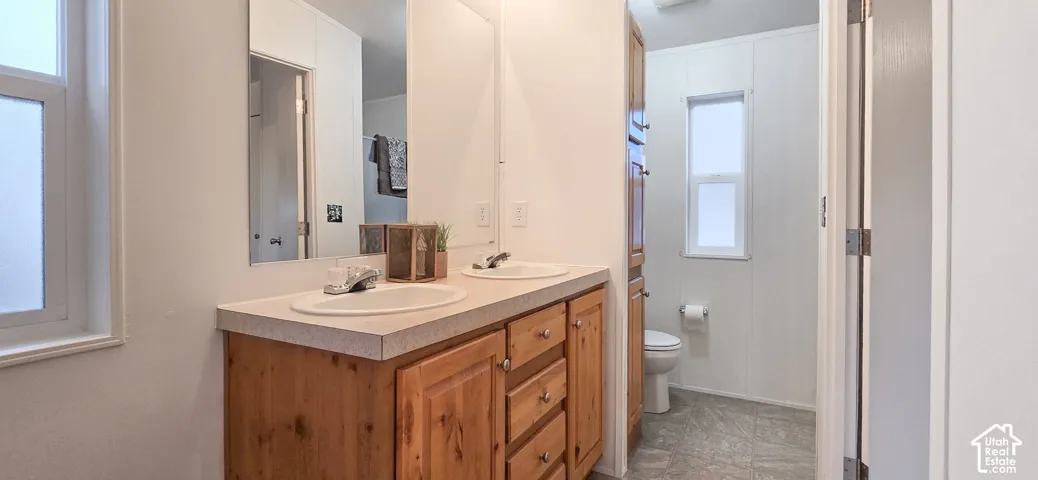 Double vanity with light wood-finish cabinetry, dual undermount sinks, and a light-toned countertop
