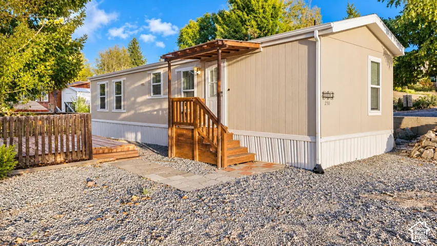 Exterior featuring tan siding, white trim, and a gravel yard