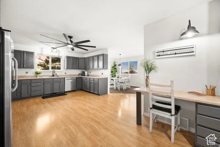 Kitchen featuring wood-finish flooring, gray cabinetry, stainless steel appliances, and a built-in desk area