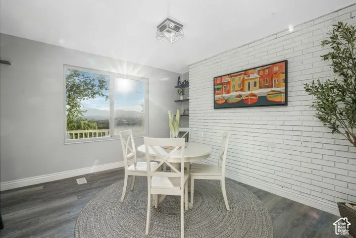 Wood-finish flooring, white brick accent wall, recessed ceiling light, and built-in shelving