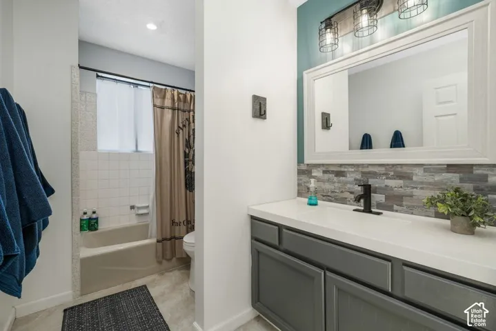 Single vanity with a white countertop and gray cabinetry, complemented by a stack stone backsplash