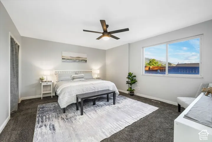 Neutral wall color, dark carpeting, and a ceiling fan with integrated lighting