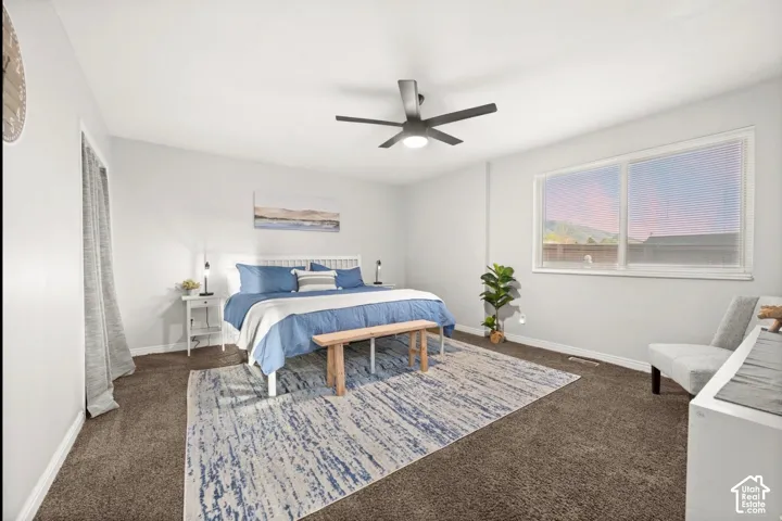 Spacious room with plush carpeting, a large window, and a ceiling fan