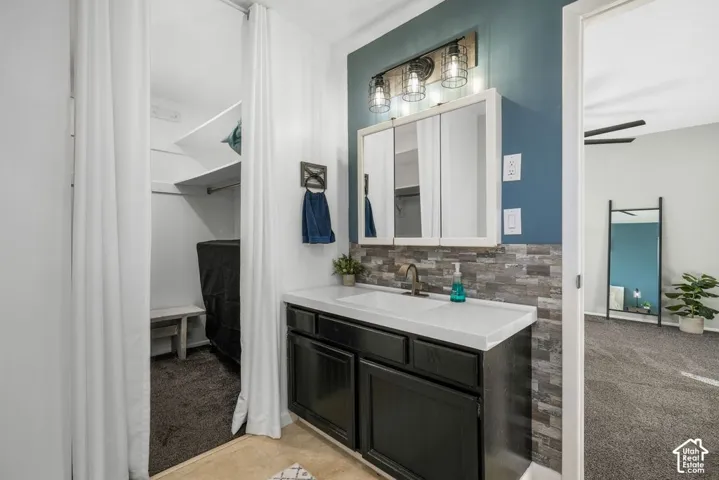 Vanity with white countertop, dark cabinetry, and bronze-finish faucet