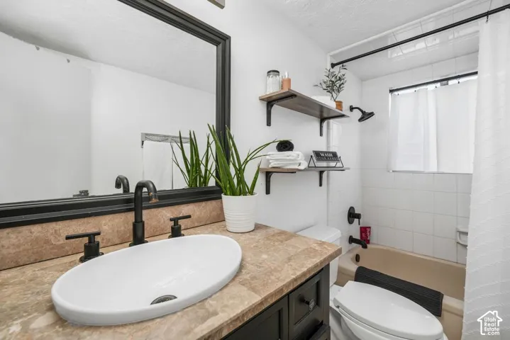 Vanity with a vessel sink and matte black fixtures, brown-toned countertop, and a framed mirror
