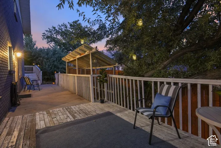 Expansive outdoor deck with wood-finish decking, white railing, and a covered structure