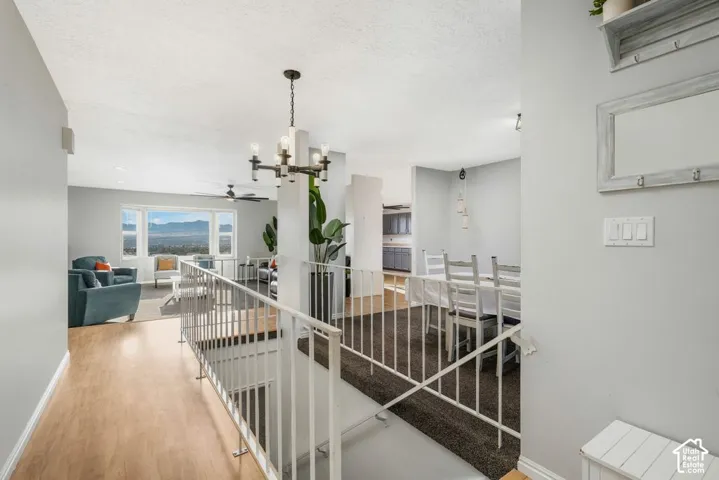 Open-concept living area with wood-finish flooring, a contemporary chandelier, and a large window framing expansive mountain scenery