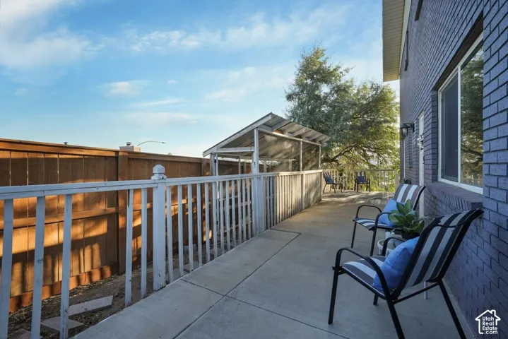 Concrete patio with a white railing, a wooden privacy fence, and a screened-in structure