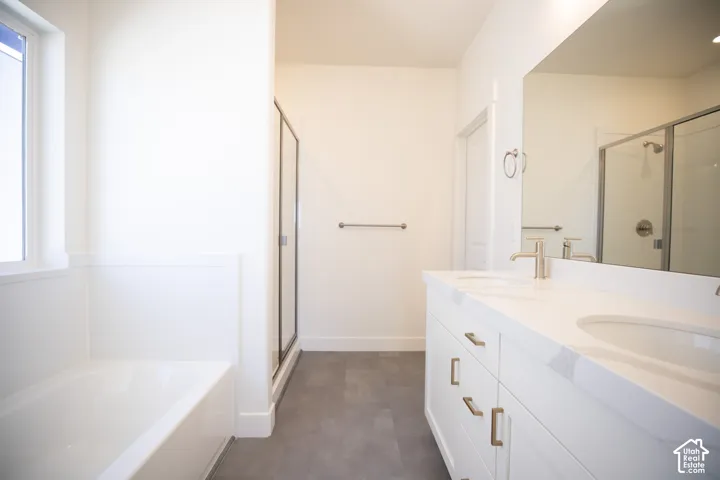 Primary bath with dual sinks, painted white wood cabinets, quartz slab countertops, soaker tub and large, walk-in shower.