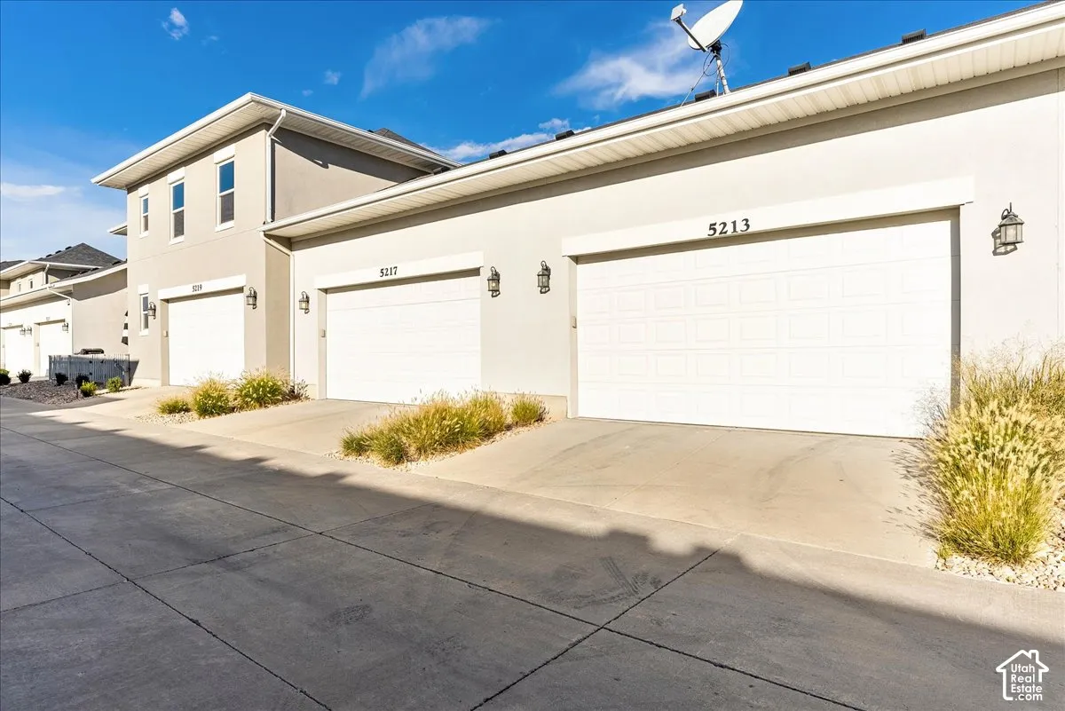 Stucco exterior with multiple garage doors, each featuring exterior lighting fixtures