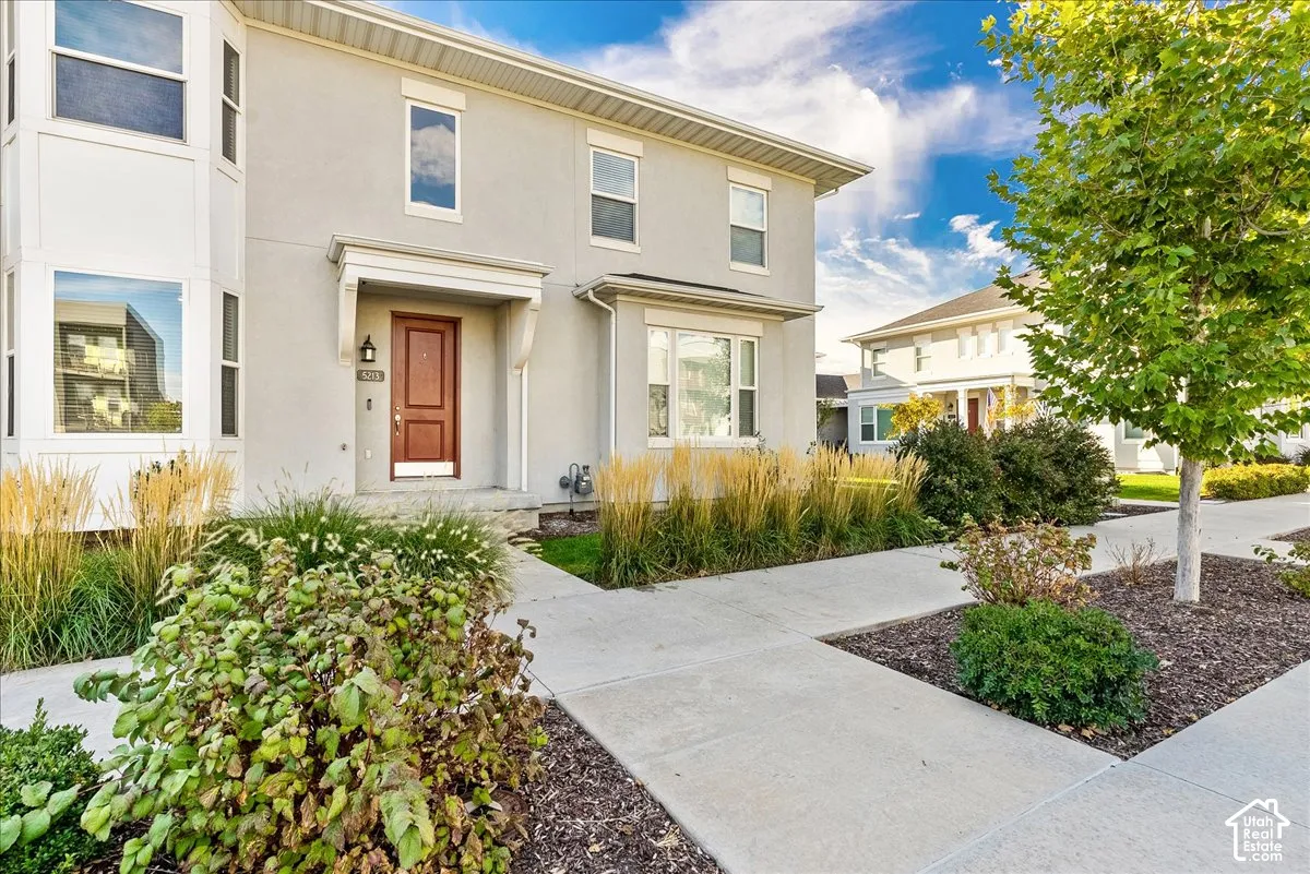 Stucco exterior featuring a prominent bay window, covered entry, and mature landscaping