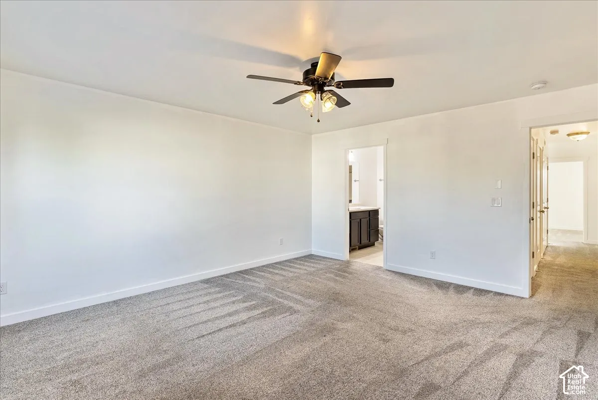Spacious room with light gray carpeting, neutral wall color, and a ceiling fan with integrated lighting