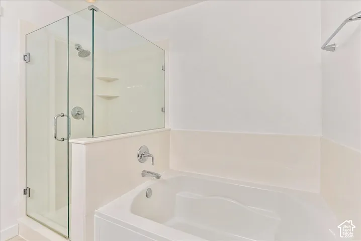 Enclosed glass shower with built-in shelving, combined with a separate soaking tub featuring chrome fixtures
