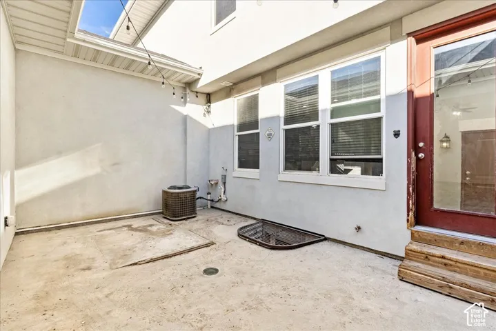 Private concrete patio featuring white stucco walls and multiple windows