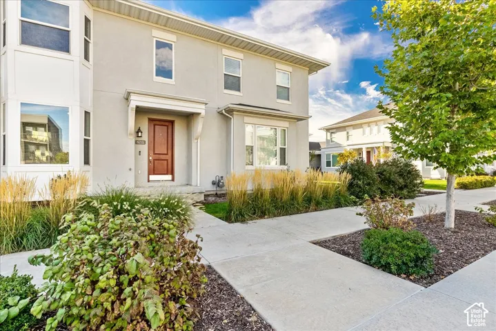 Stucco exterior featuring a prominent bay window, covered entry, and mature landscaping