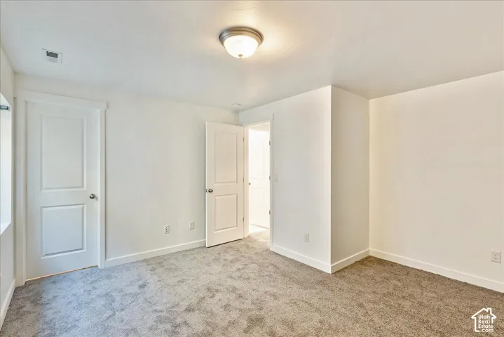 Light gray carpeted flooring, neutral wall tones, white trim, and a semi-flush mount ceiling light fixture