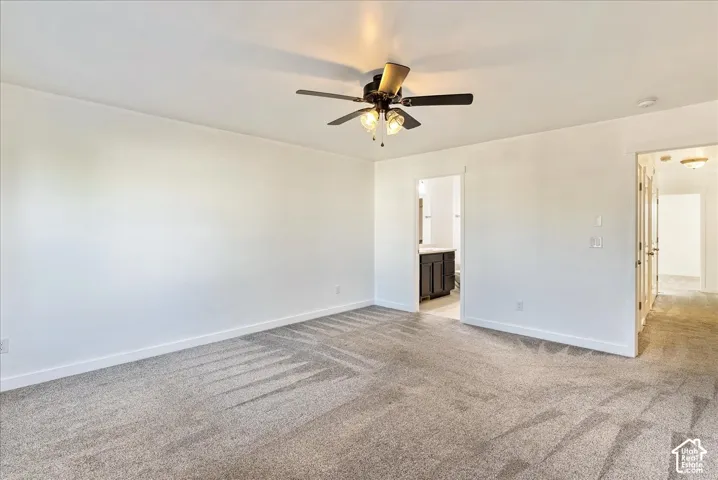 Spacious room with light gray carpeting, neutral wall color, and a ceiling fan with integrated lighting