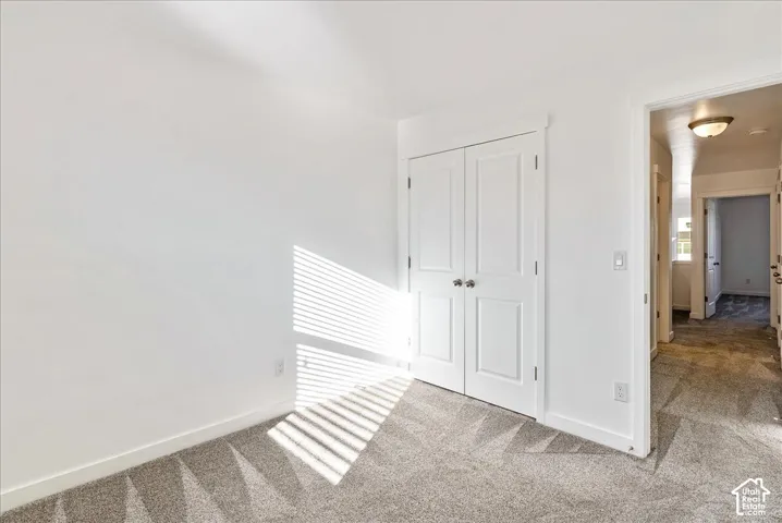 Plush gray carpeting, white painted walls, and white bi-fold closet doors