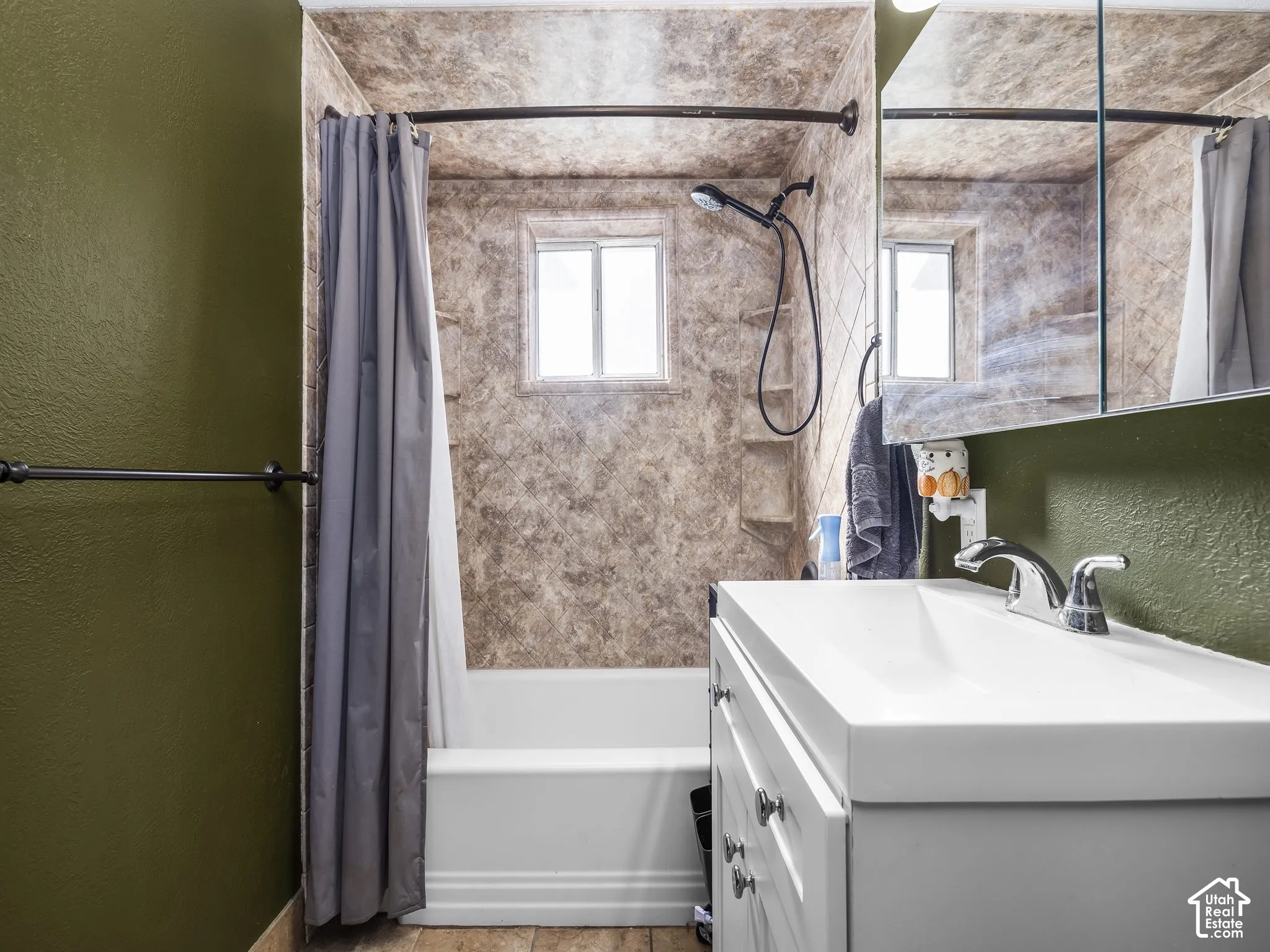 White vanity with a single basin sink and chrome faucet, integrated medicine cabinet, and white bathtub with a shower kit