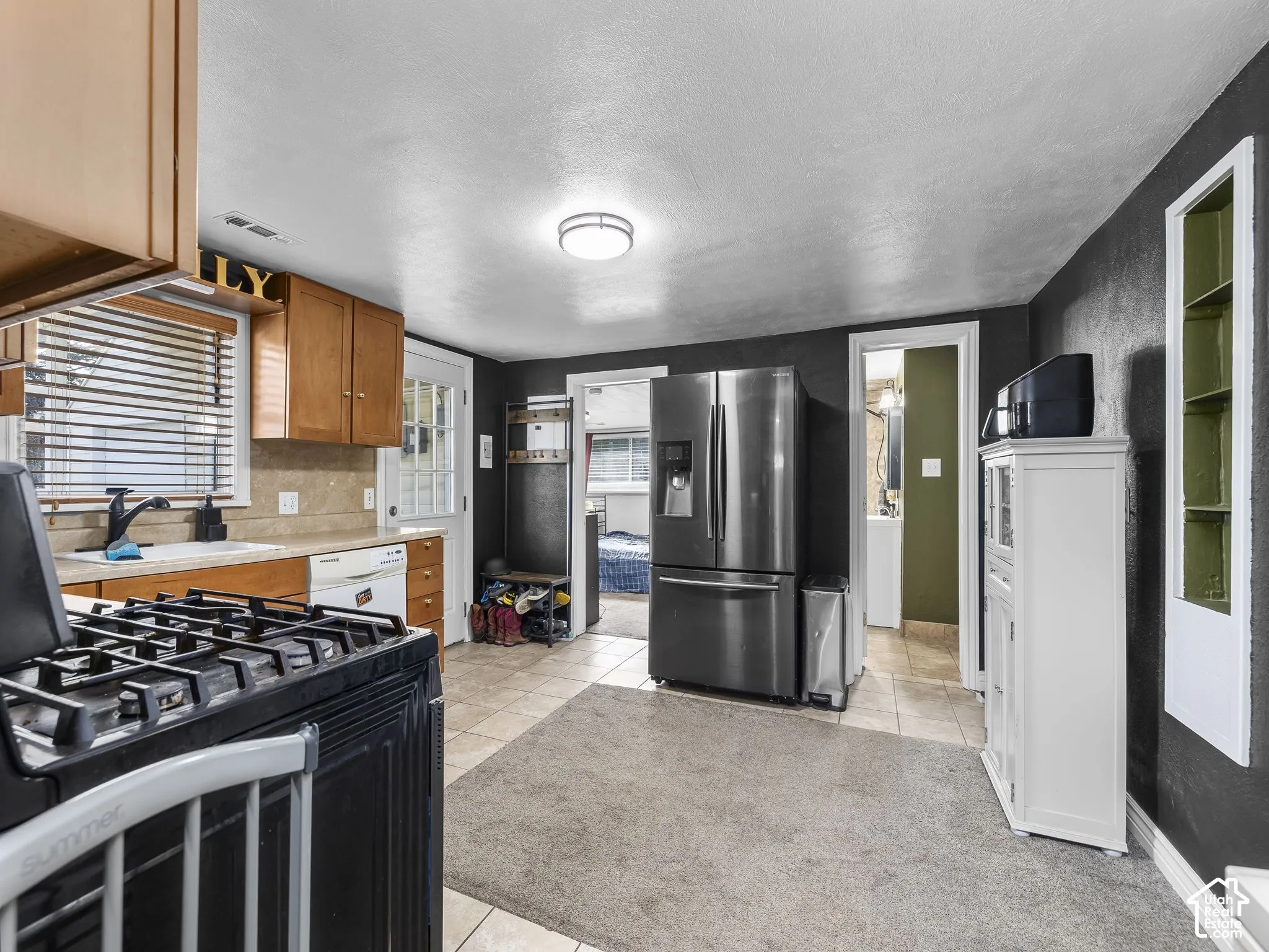 Kitchen featuring wood cabinetry, a gas range, a double-basin sink, and tile flooring