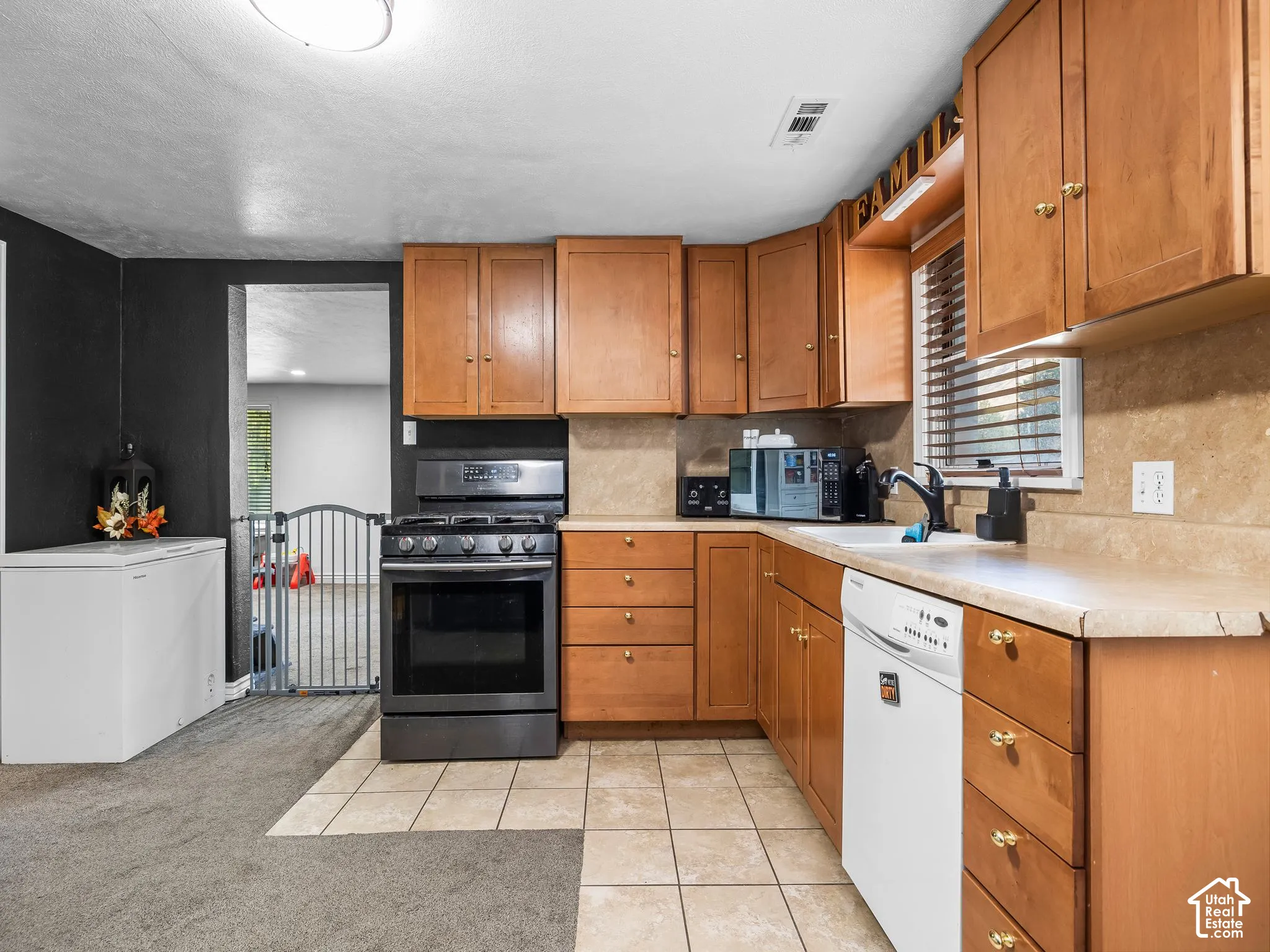 Kitchen featuring wood-finish cabinetry, tile flooring, stone-look countertops, and stainless-steel appliances