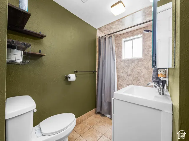 White vanity with integrated sink, chrome faucet, wall-mounted mirror, and tile flooring