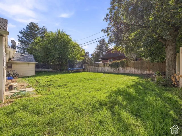 Expansive grassy yard with mature trees and a privacy fence