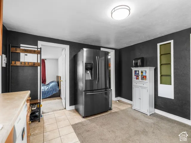 Stainless steel refrigerator, tile flooring, and overhead flush-mount lighting