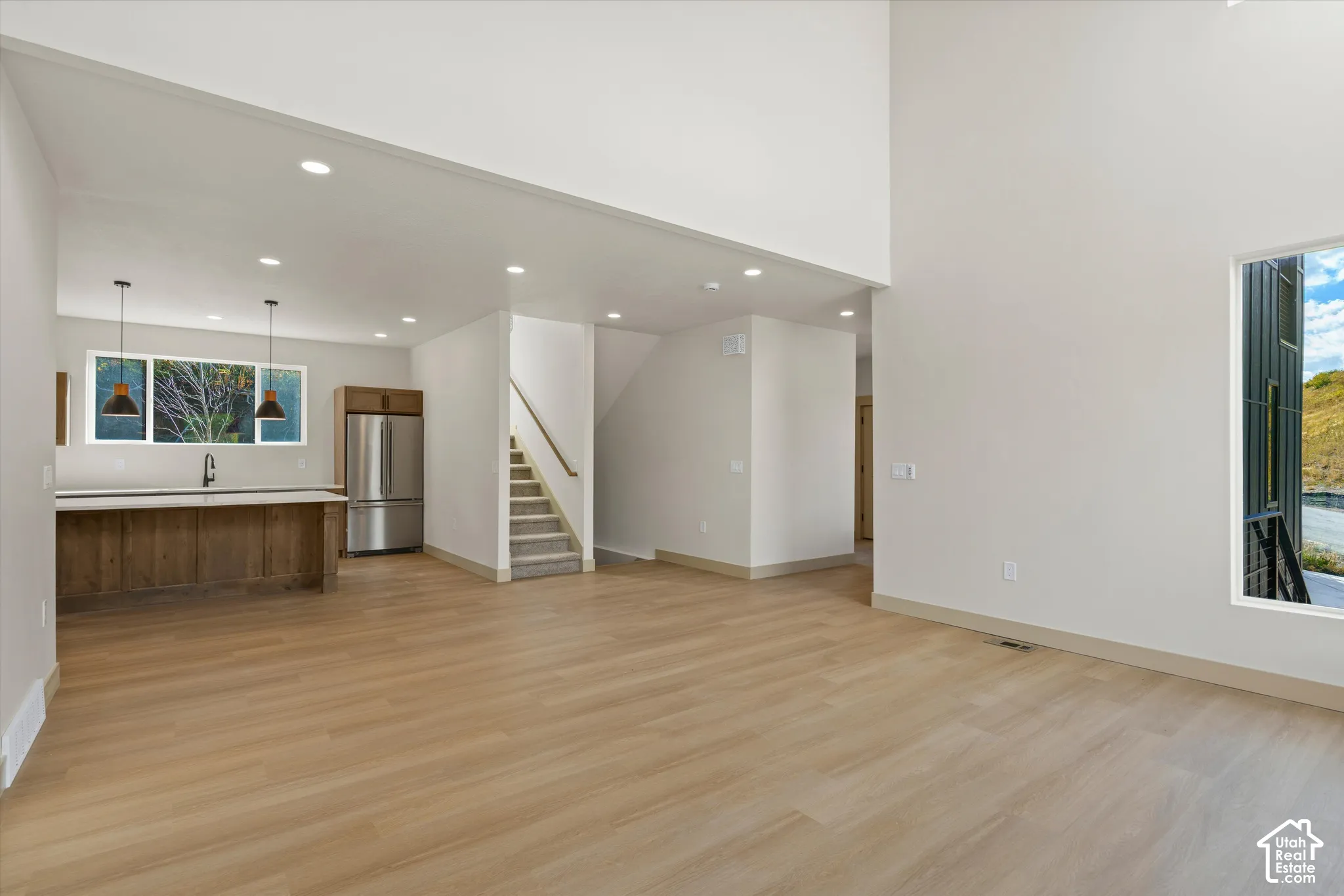 Two-story living area with wood-finish flooring, recessed lighting, and a prominent window