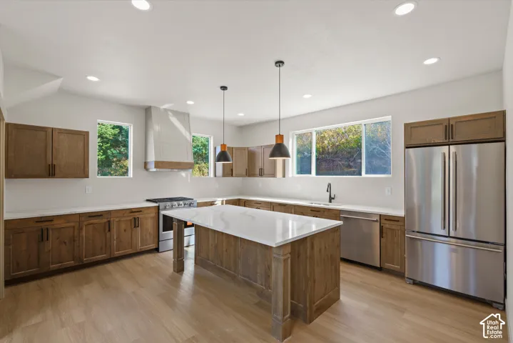 Spacious kitchen featuring wood-finish cabinetry, stainless steel appliances, a center island with a white countertop, and recessed lighting