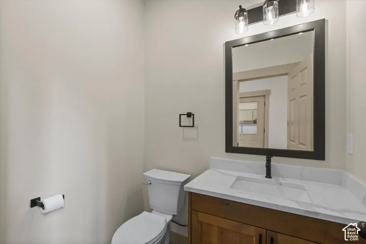 Solid wood vanity with integrated sink, white countertop, matte black faucet, framed mirror, and three-light vanity fixture
