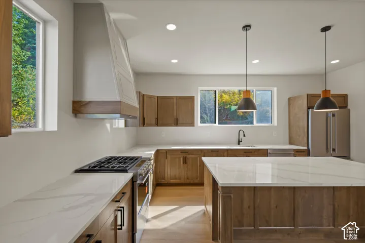Kitchen featuring a gas range, stainless steel appliances, wood-finish cabinetry, white countertops, and pendant lighting