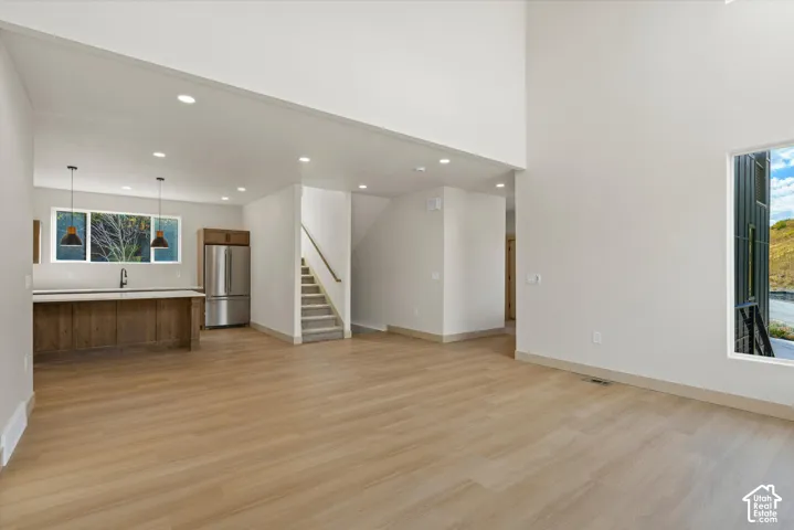 Two-story living area with wood-finish flooring, recessed lighting, and a prominent window